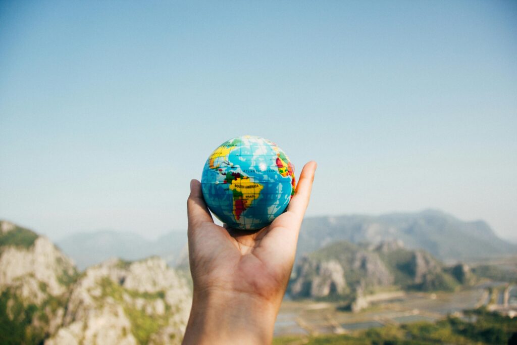 pexels photo 346885 346885 Hand holding a globe against a mountain background symbolizing travel and exploration.